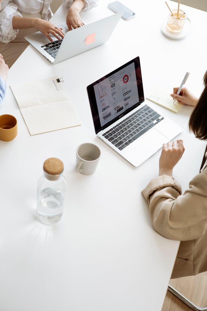 High angle view of businesswomen working with laptops and documents at a modern office desk.